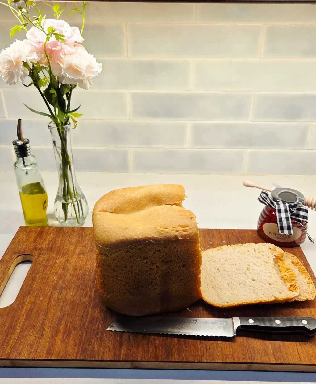 A freshly baked loaf of bread sits on a cutting board with a knife placed next to it.
