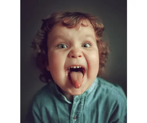 a child with curly hair sticking out his tongue