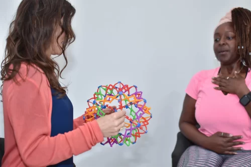 Yoga Therapist using hoberman sphere to teach breathing to a woman with hands on her chest and abdomen